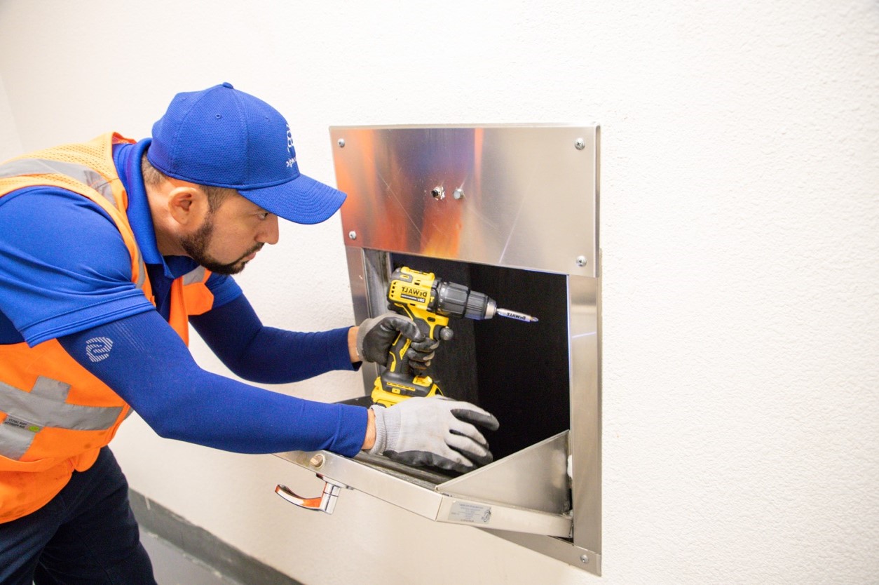 Strategic service technician repairing a multifamily trash chute door