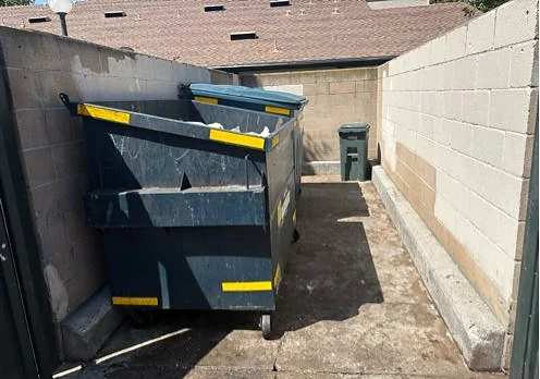 Dumpster enclosure with loose trash cleared from the ground at Aliso Creek Villas HOA after service