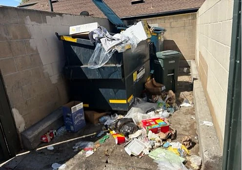 Overflowing dumpster and scattered trash across the enclosure at Aliso Creek Villas HOA before service