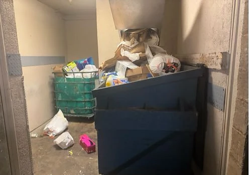 Bags and cardboard piled beneath the trash chute at City Lights Apts before service