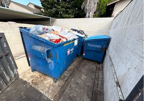 Blue bins with the surrounding enclosure floor cleared at Horizon Apts after service
