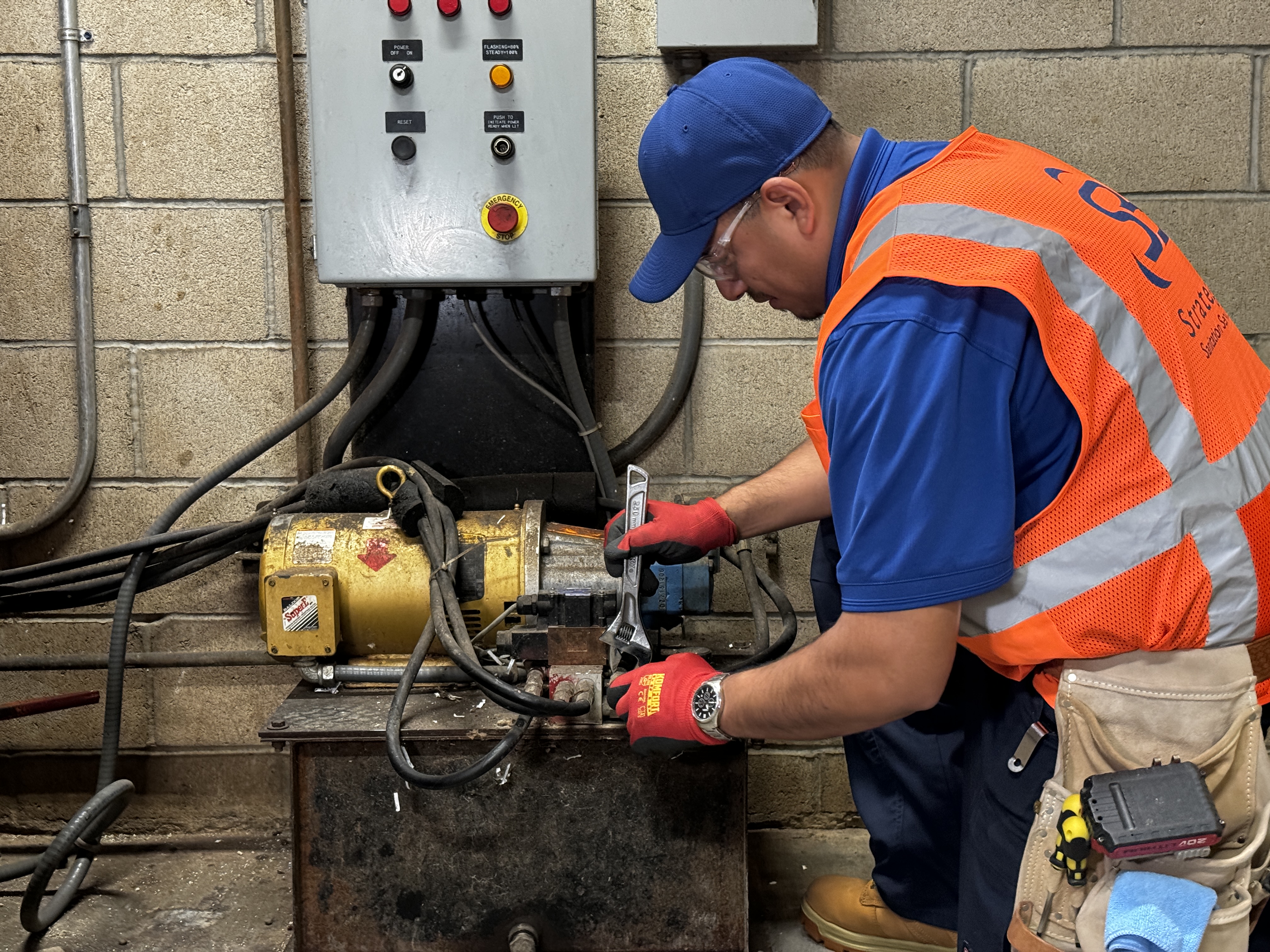 Strategic technician servicing compactor hydraulic equipment with a wrench