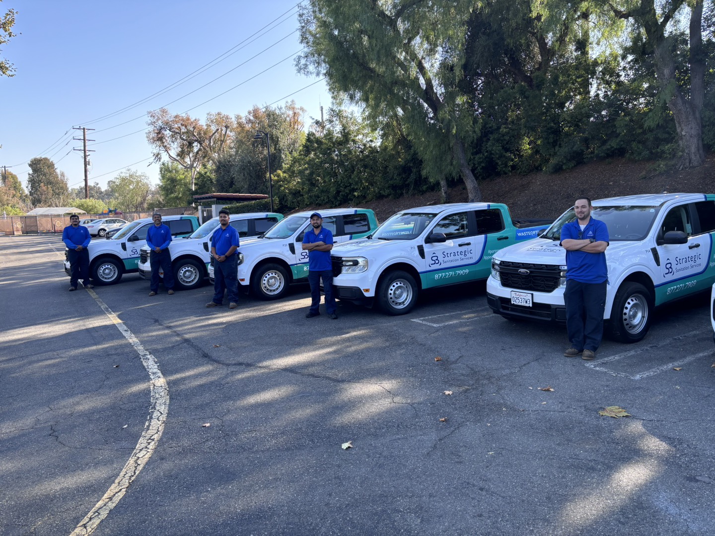 Strategic Sanitation Services route technicians standing beside their service trucks